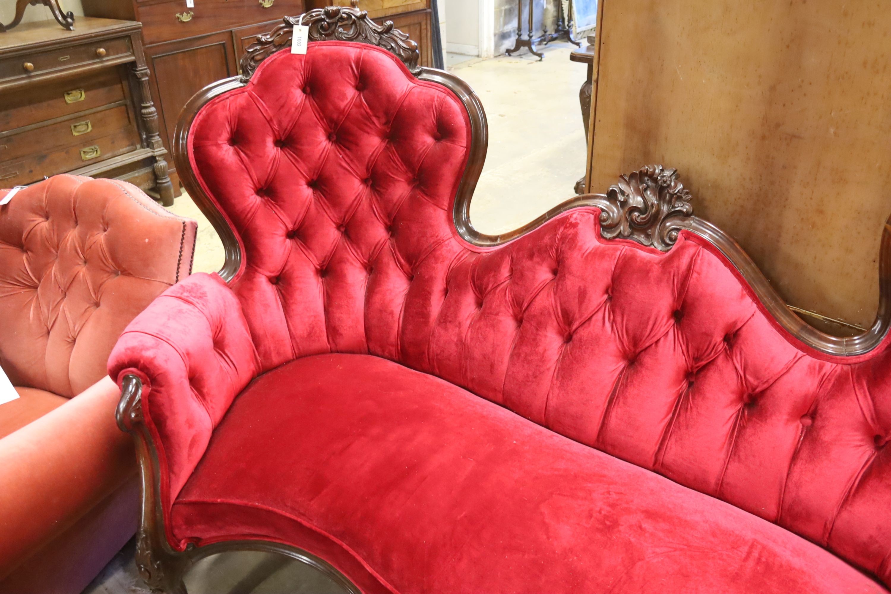 A Victorian carved rosewood double spoon back settee upholstered in deep buttoned scarlet velvet, length 200cm, depth 96cm, height 122cm